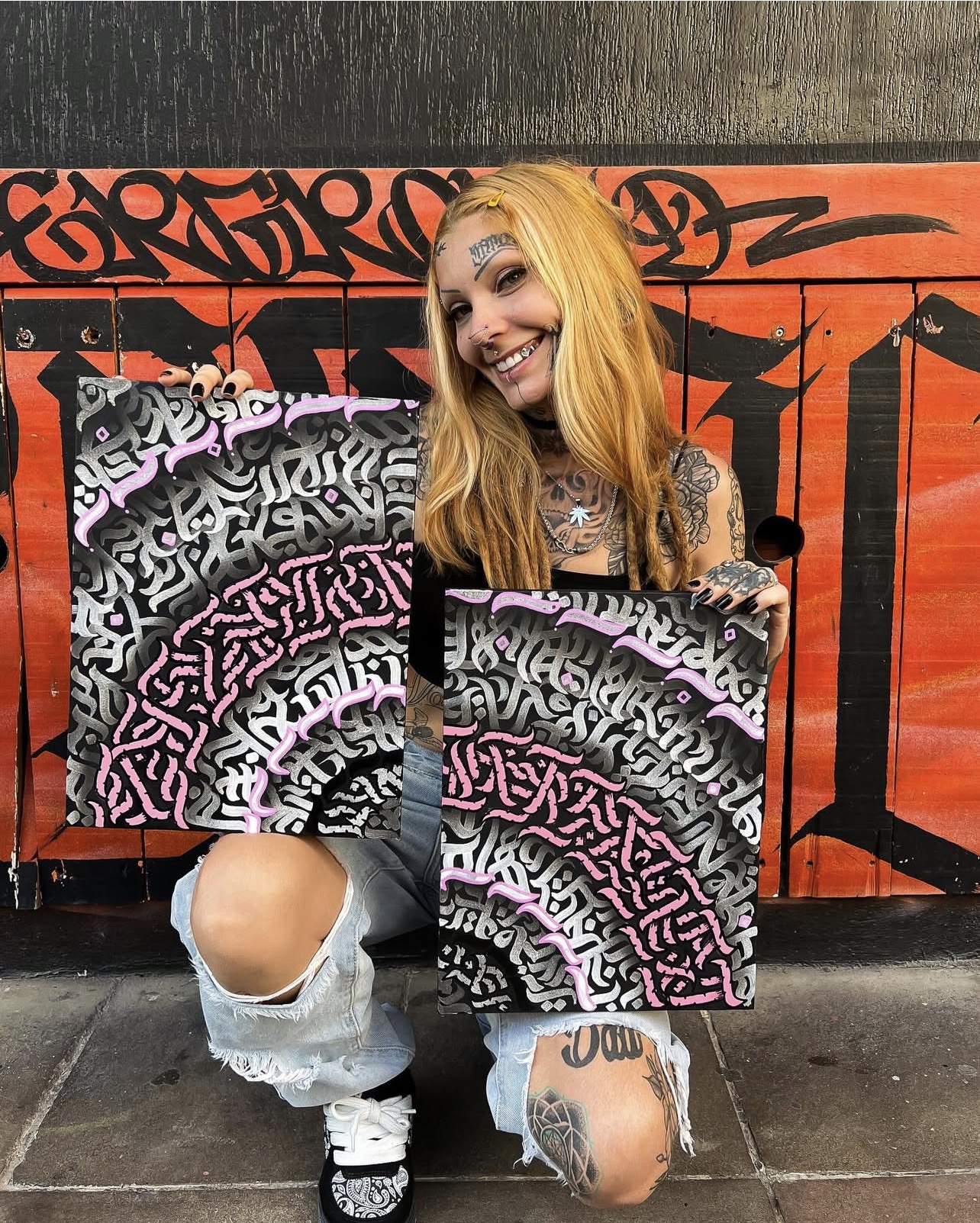 Thaís Muniz segurando duas de suas artes de lettering